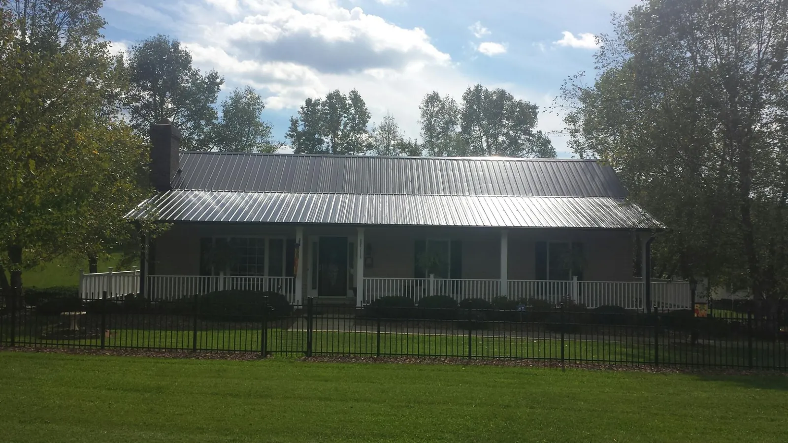 Gray metal roof on a brick ranch with a full width front porch — Gutter Guard Installation work by our crew in Foley