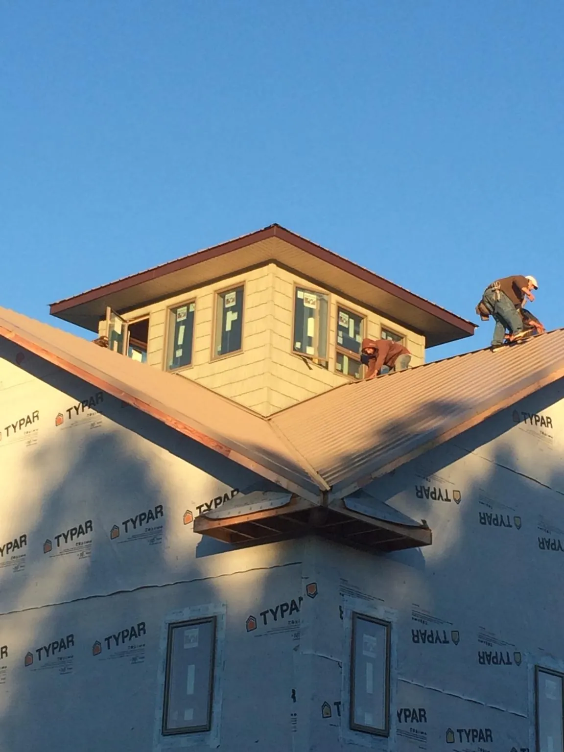 Roofers working around a rooftop cupola on a new metal roof at sunset — Roof Waterproofing in Foley by Roofing Brothers
